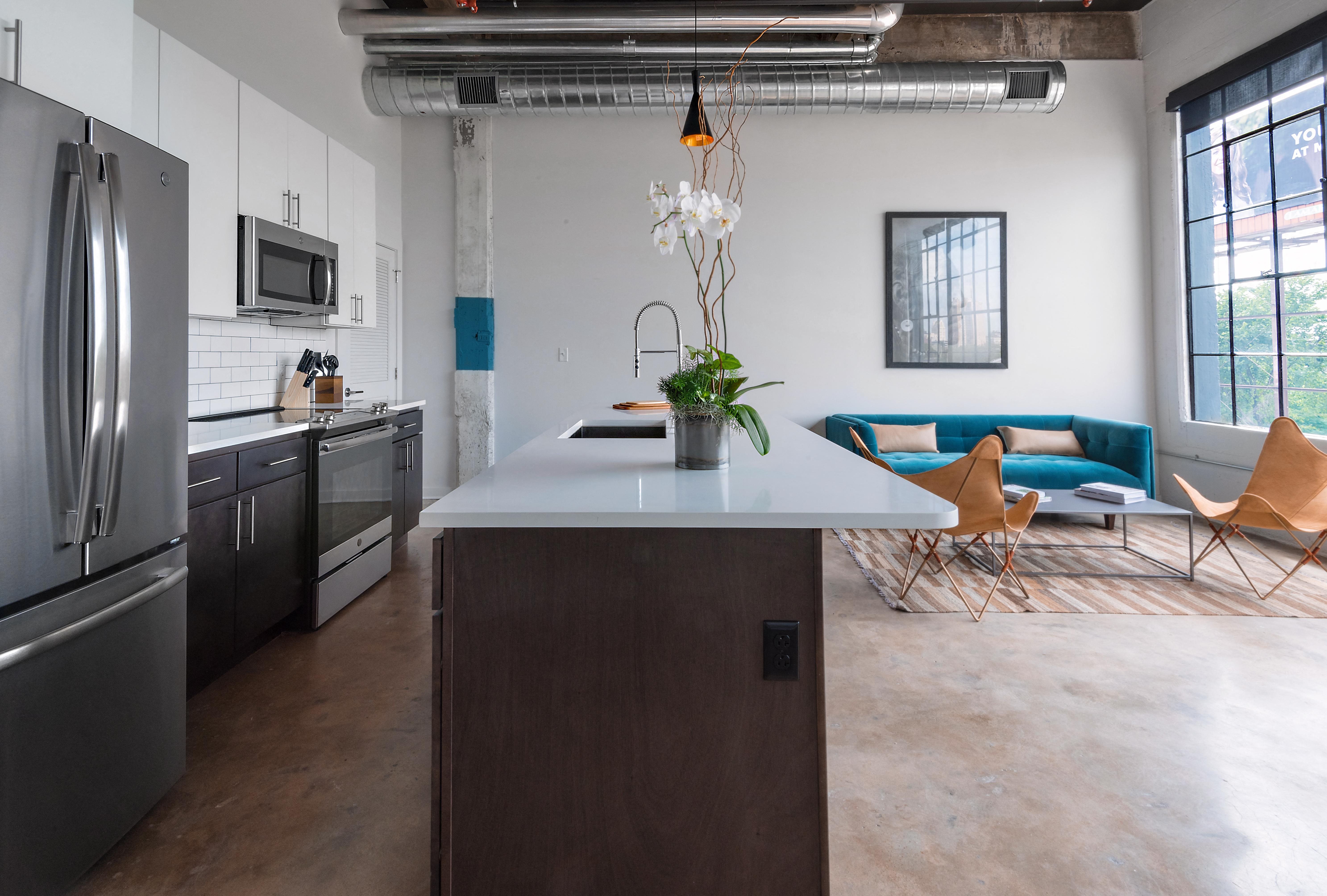 a kitchen with an island and a living room in the background